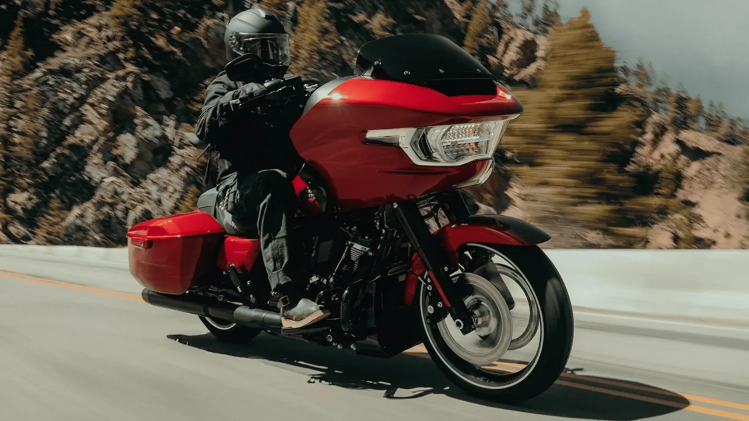 A man rides a red Harley-Davidson® Road Glide® motorcycle on a sunny highway in Stuart, FL, enjoying the open road.