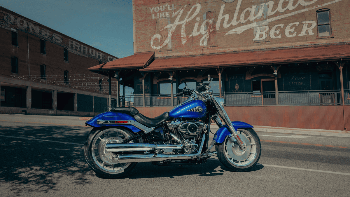 2025 Harley-Davidson® Fat Boy® in brilliant blue parked in front of vintage Sanford, FL brick building—built for bold riders