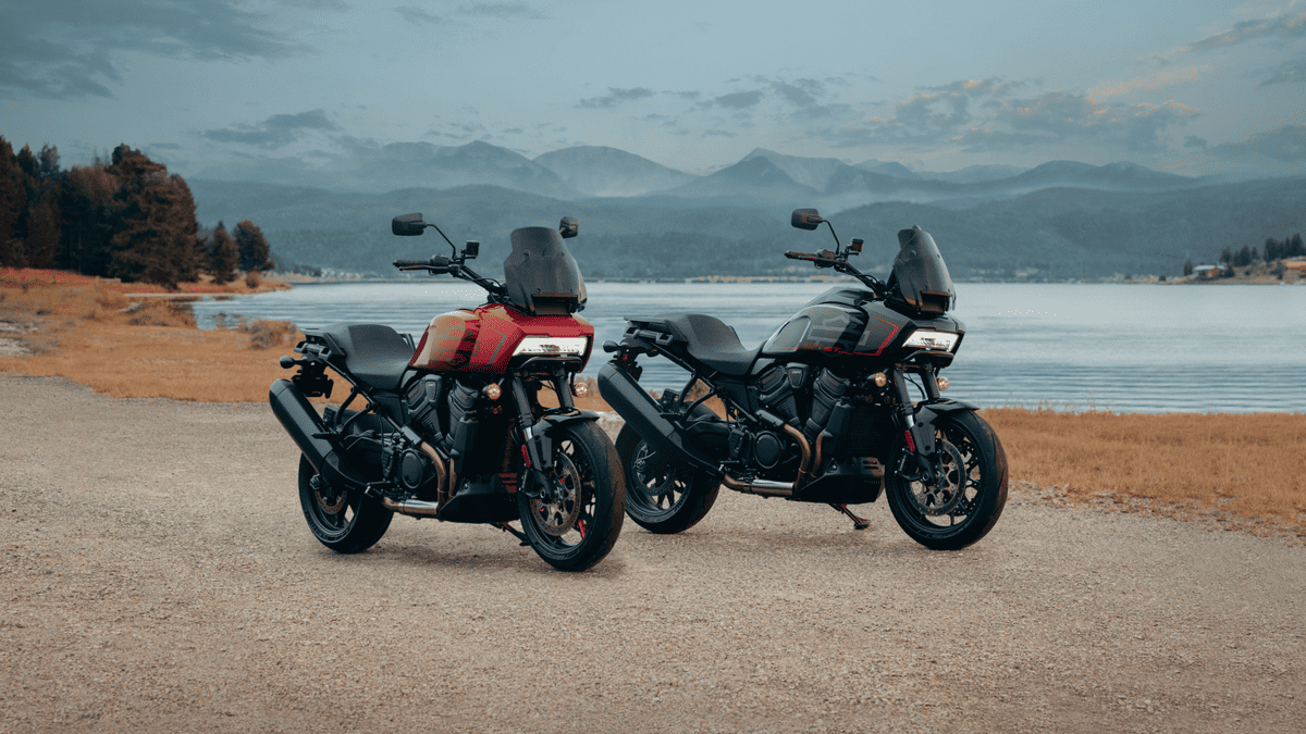 Two 2025 Harley-Davidson® Adventure Touring motorcycles parked by a lakeside with mountains in the background, showcasing rugged dual-sport design and scenic-ready performance.