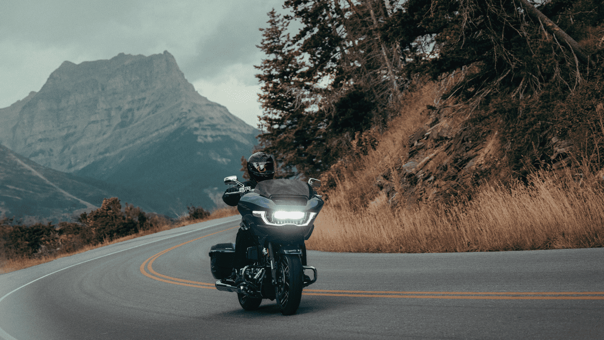 Rider leaning into a curve on a 2025 Harley-Davidson® CVO™ Road Glide® near Sanford, FL, with mountain backdrop and LED lights on.