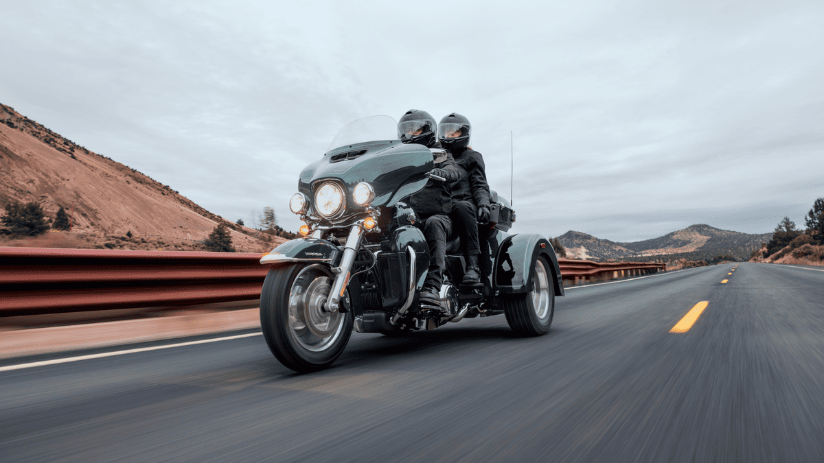 2025 Harley-Davidson® Tri Glide® Ultra with two riders cruising on an open road near Sanford, FL, showing off comfort, control & three-wheel touring power.