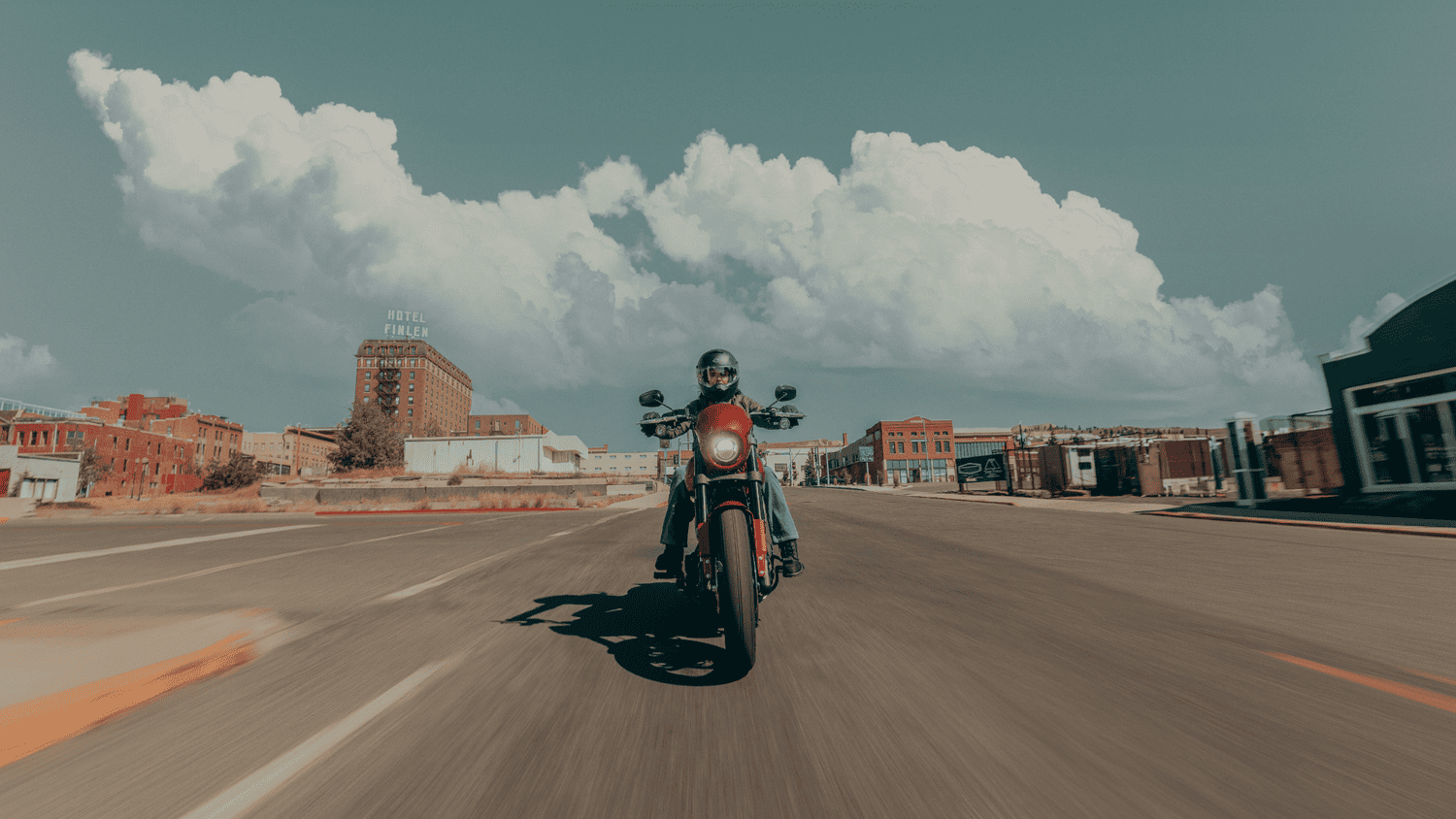 Front view of 2025 Harley-Davidson® Low Rider® S riding through a downtown street near Sanford, FL with bold city architecture behind.