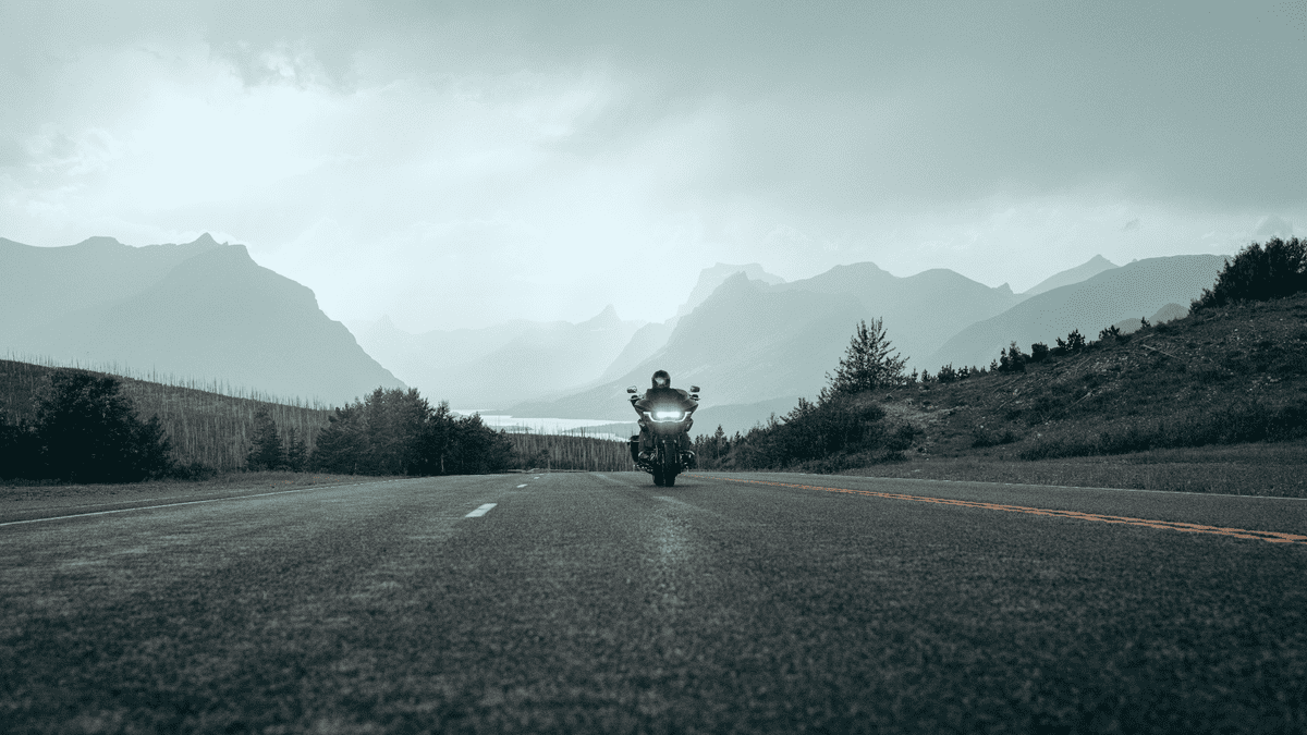 2025 Harley-Davidson® CVO™ Road Glide® riding down an open highway near Sanford, FL, with its adaptive headlight system shining through scenic mountains.