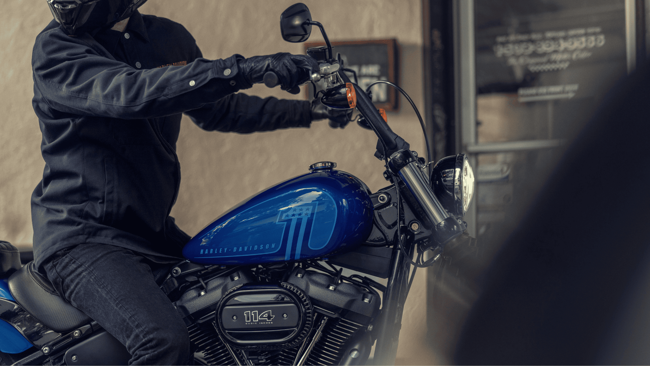 Close-up of a motorcyclist riding a blue Harley-Davidson Street Bob 114.