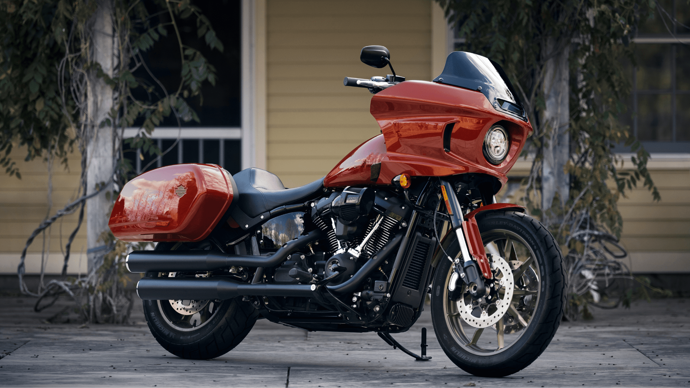 A red Harley-Davidson Low Rider® ST motorcycle parked in front of a yellow house.