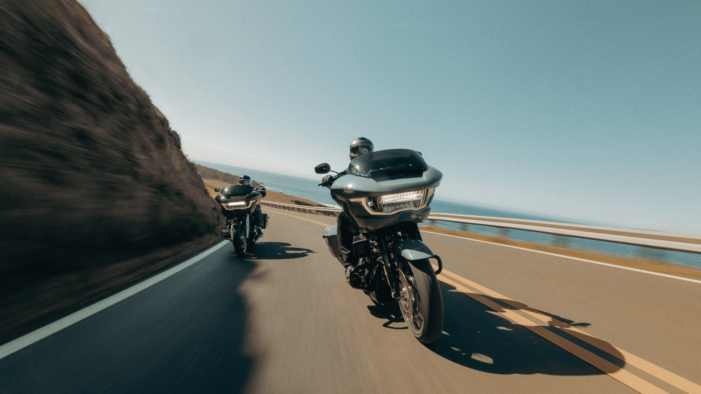 Two Harley-Davidson Road Glide motorcycles riding on a scenic coastal highway.