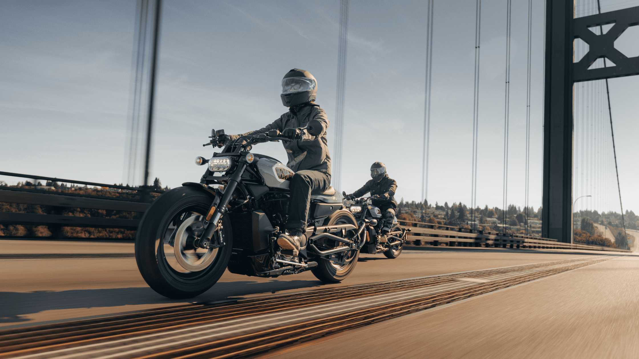 Two riders on Harley-Davidson Sportster® S motorcycles riding across a bridge.