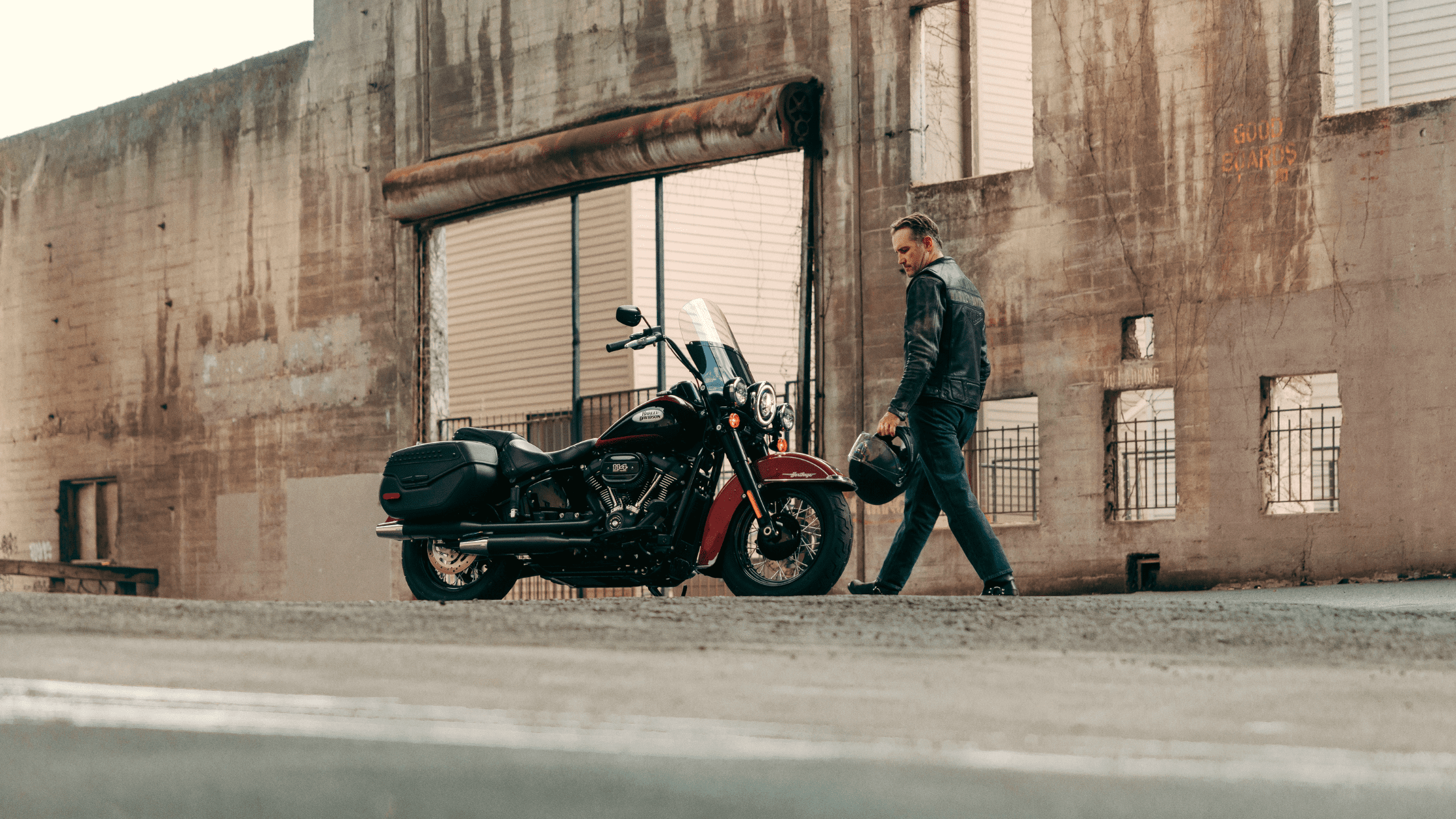 A man walking towards a parked Harley-Davidson Heritage Classic motorcycle.