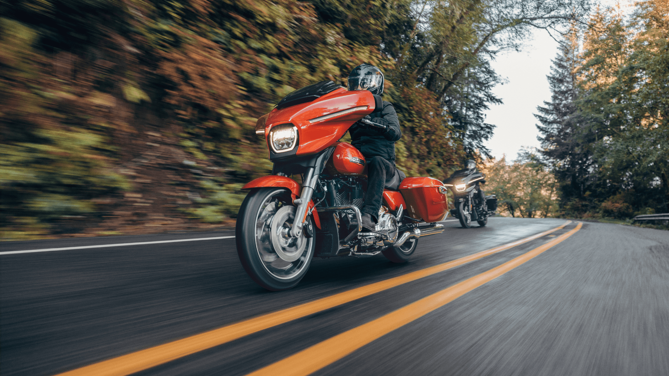 Two riders on 2024 Street Glide® motorcycles cruising on a scenic road