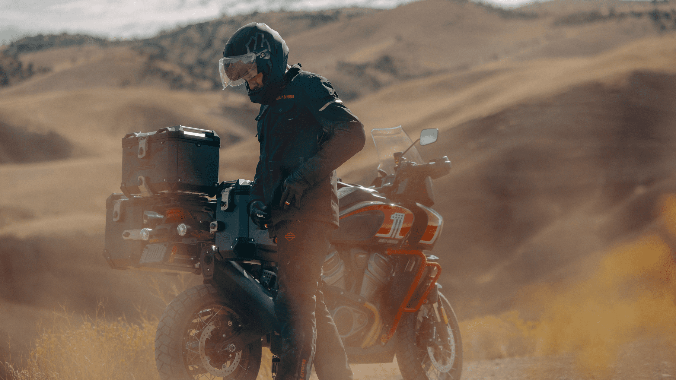 A man wearing a helmet with a CVO Pan America Harley-Davidson motorcycle