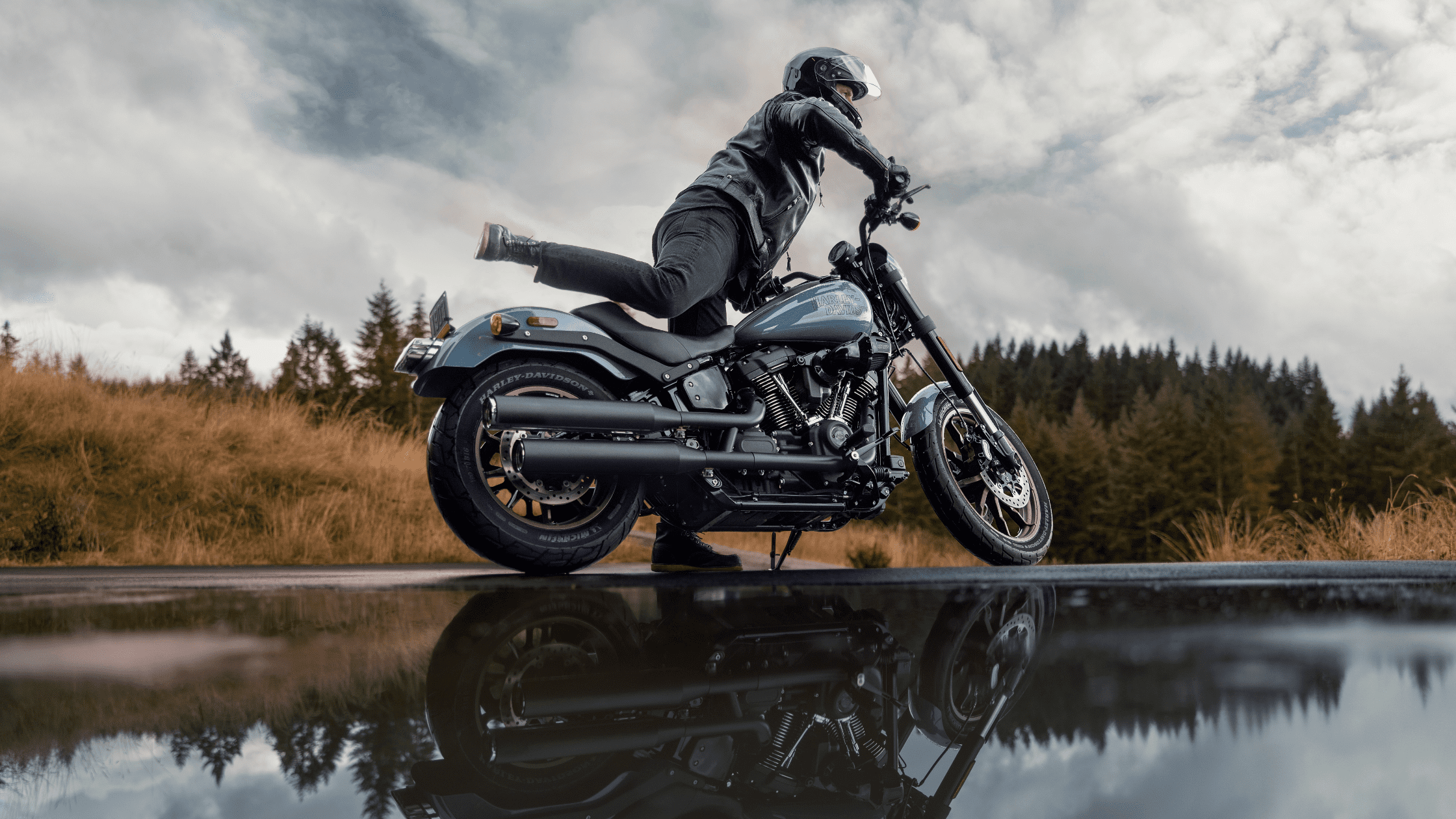 Rider mounting a Harley-Davidson Low Rider® S with reflection in water on a moody day