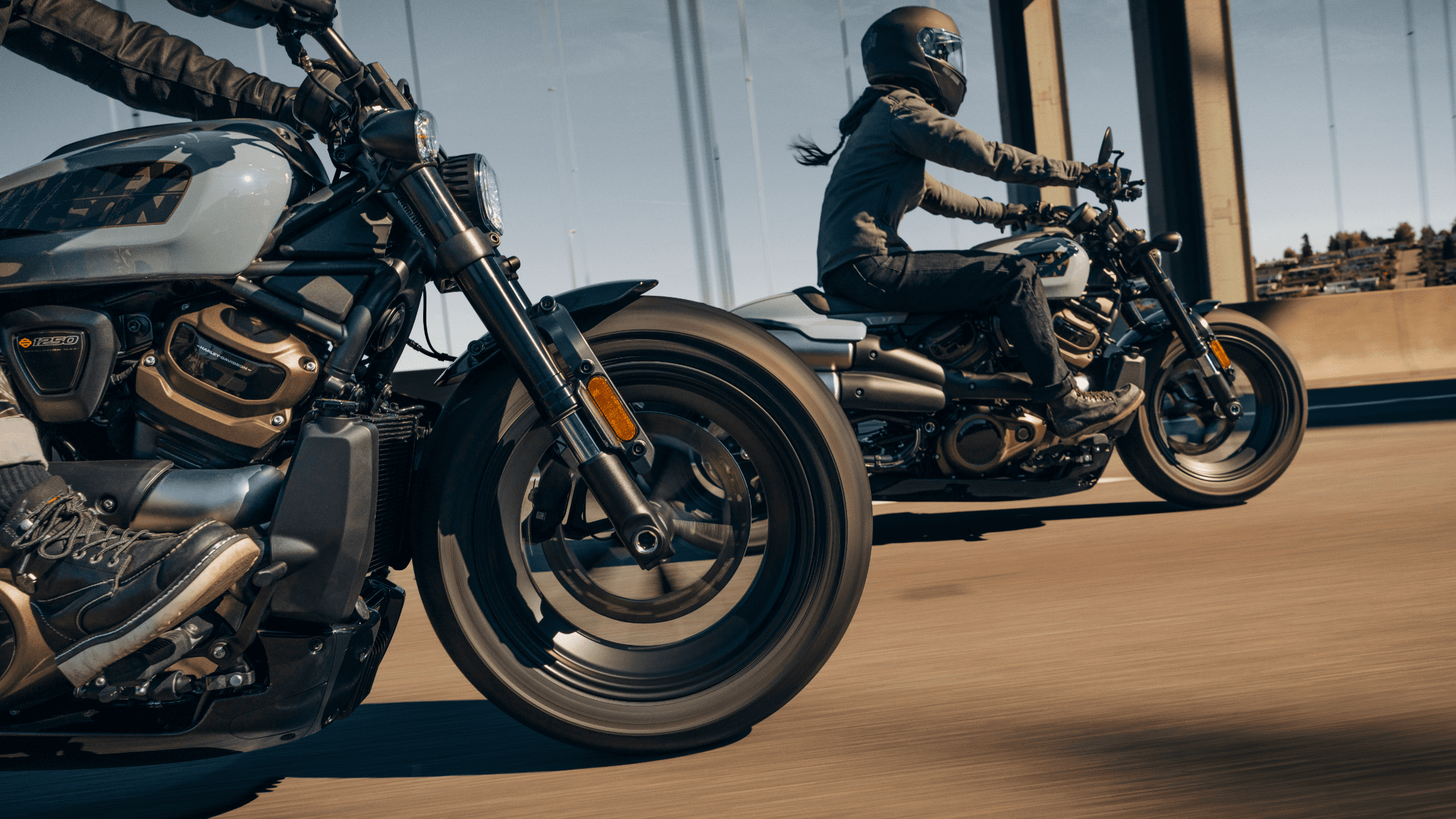 Two riders on Harley-Davidson Sportster® S motorcycles cruising across a bridge, capturing the dynamic motion and sleek design of the bikes.