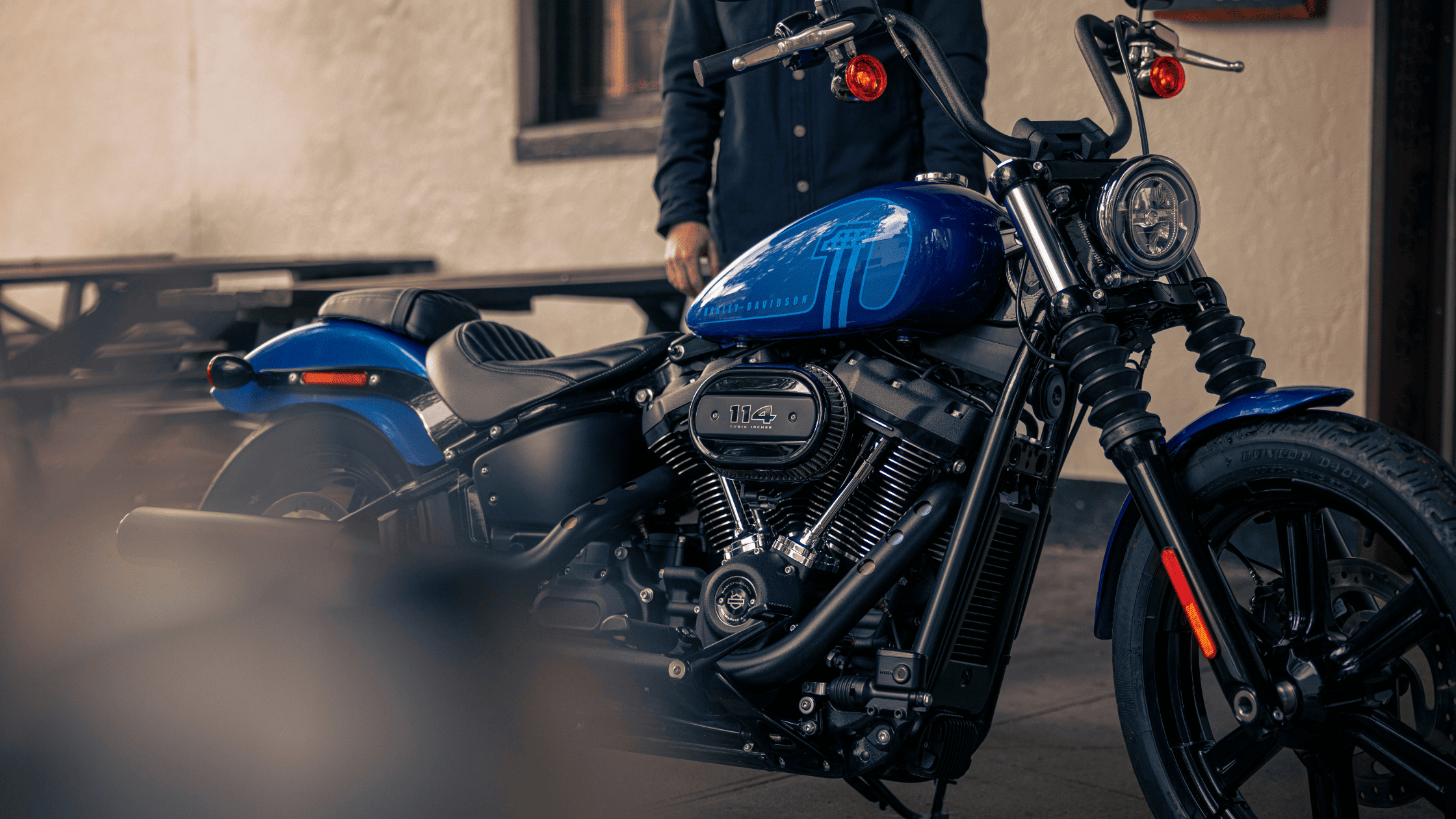 2024 Harley-Davidson® Street Bob® 114 parked near a cafe, showcasing its powerful engine and sleek design.