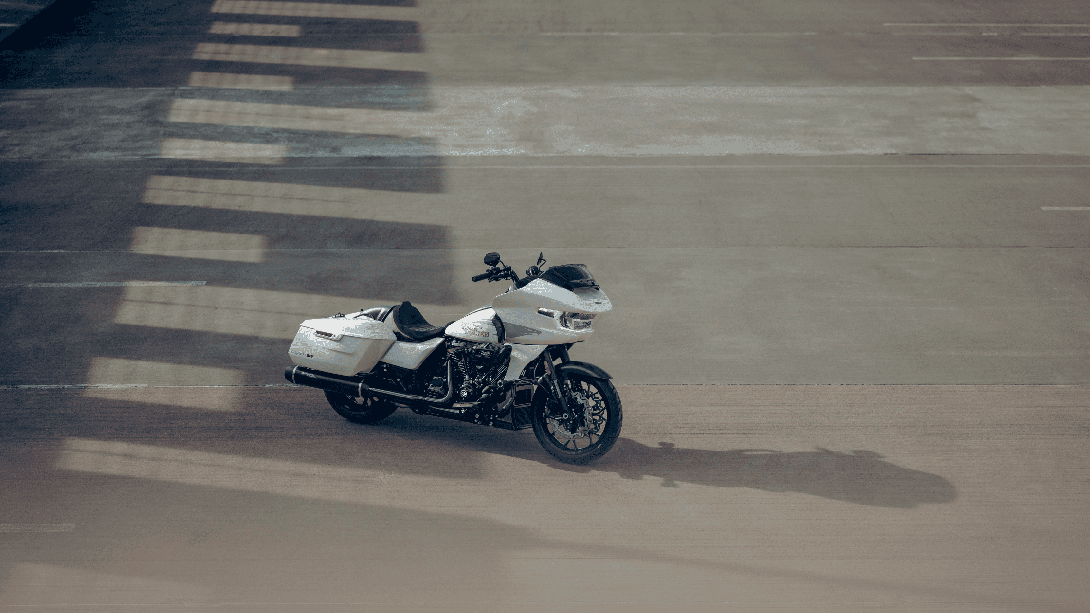 White Harley-Davidson® CVO™ Road Glide® ST motorcycle parked on a sunlit pavement with shadow patterns in the background.