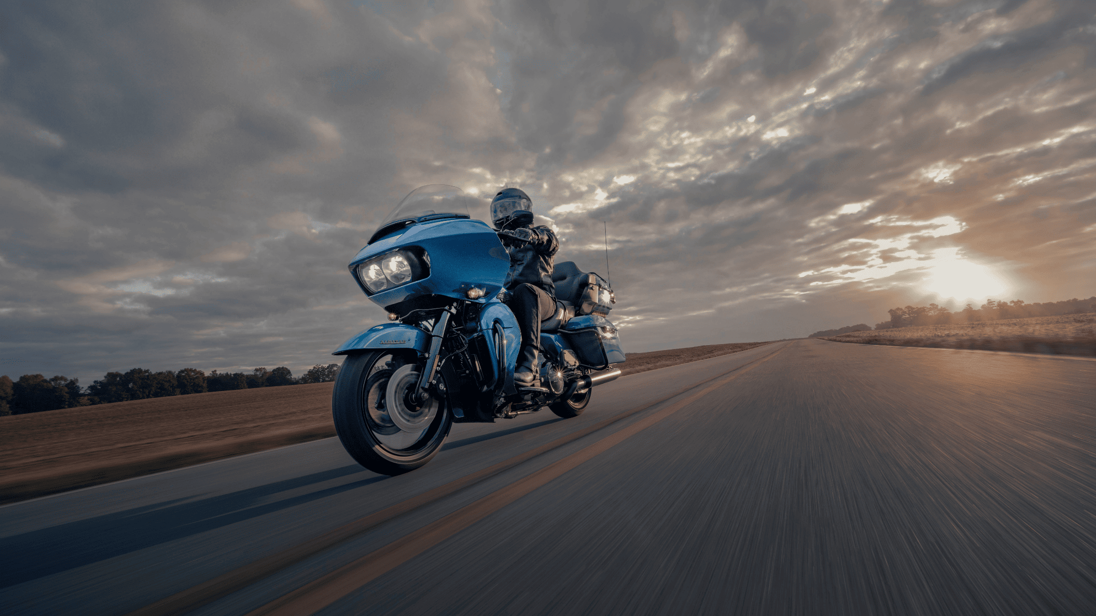 2024 Harley-Davidson® Road Glide® Limited cruising at sunset, highlighting its touring power and style.