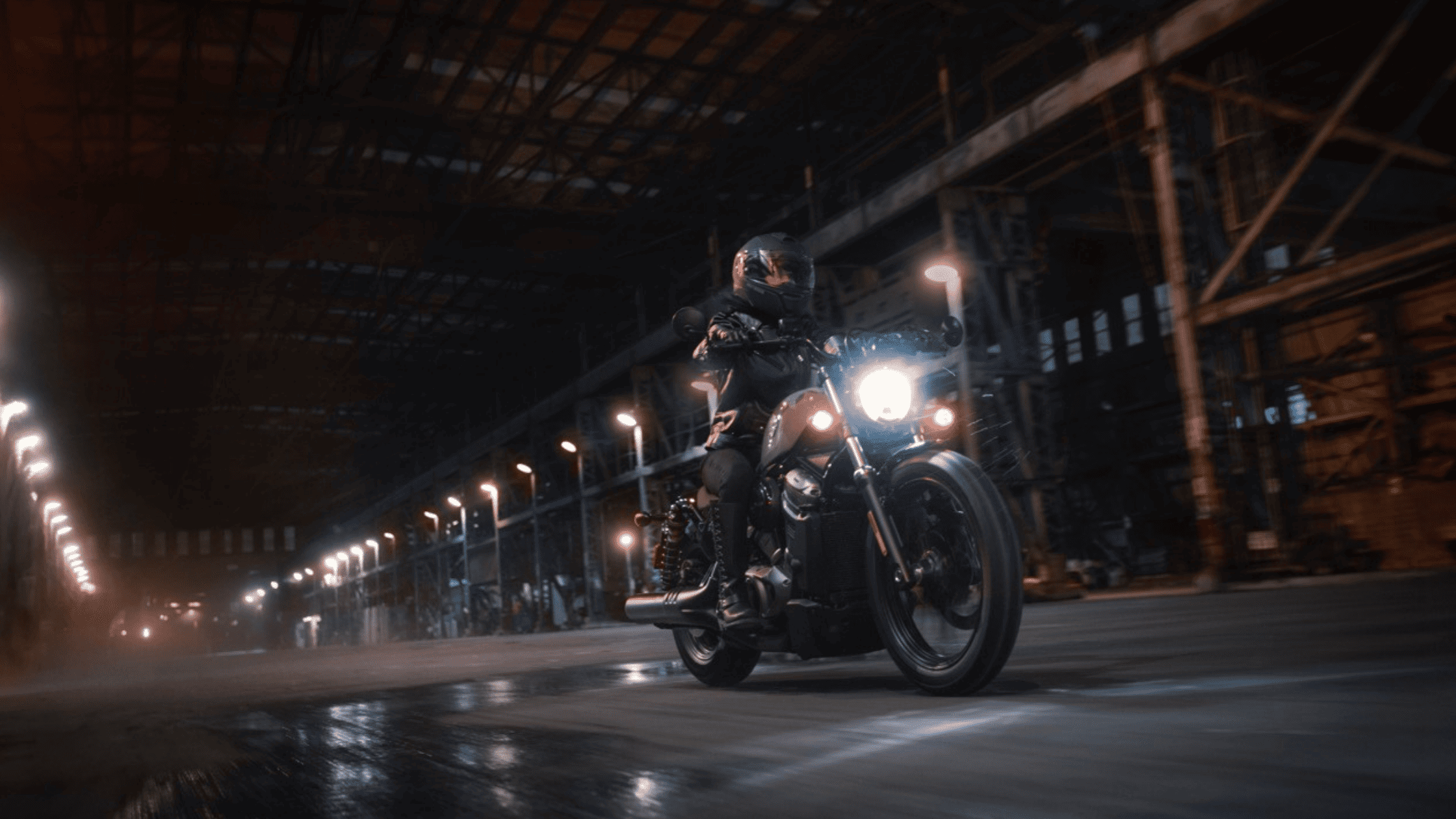 Rider on a 2024 Harley-Davidson® Nightster® cruising through a dimly lit industrial area