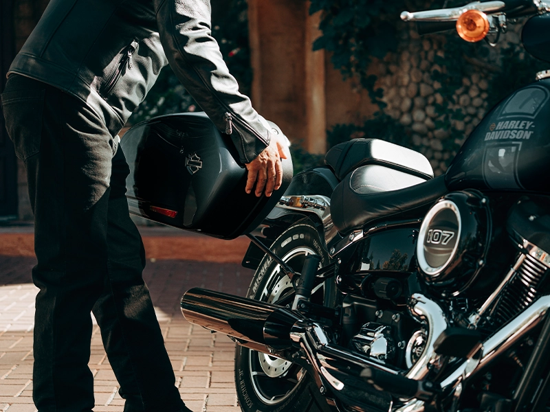 A man putting storage onto his parked up Harley-Davidson