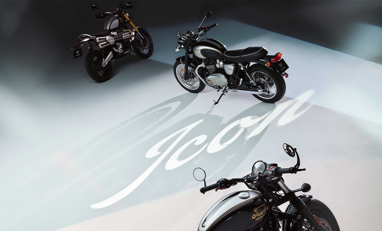A wide shot of three Triumph bikes in Sapphire Black and Aluminium Silver parked up on side stands in a warehouse