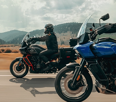 Five people riding Harley Davidson bikes under a bridge in a town setting