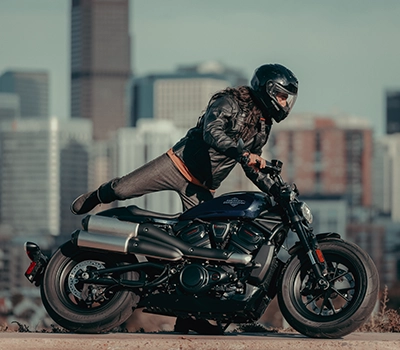 A person riding a Harley Davidson bike on a road in the woodlands