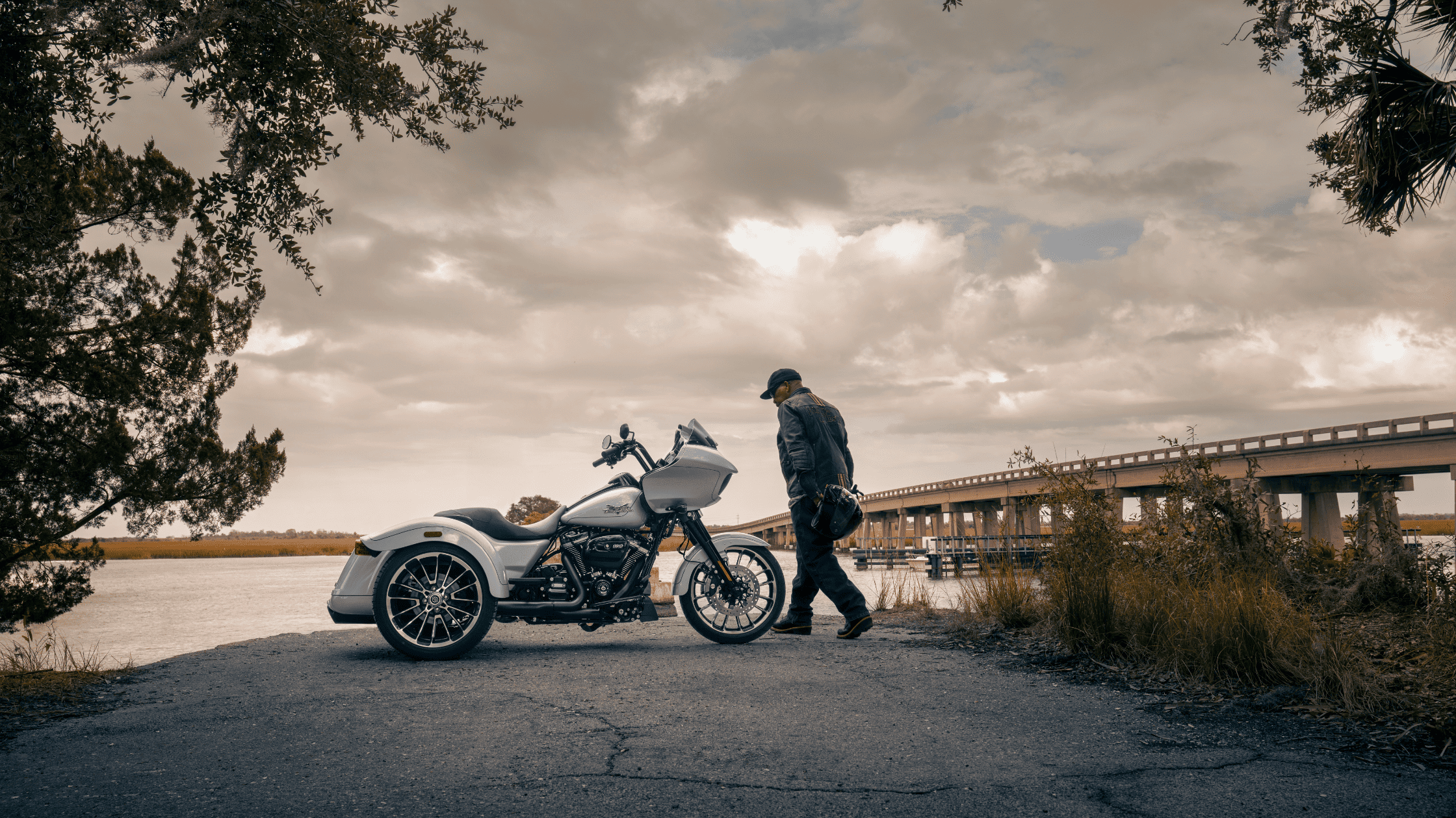 2024 Harley-Davidson® Road Glide® 3 parked by waterfront, rider nearby.