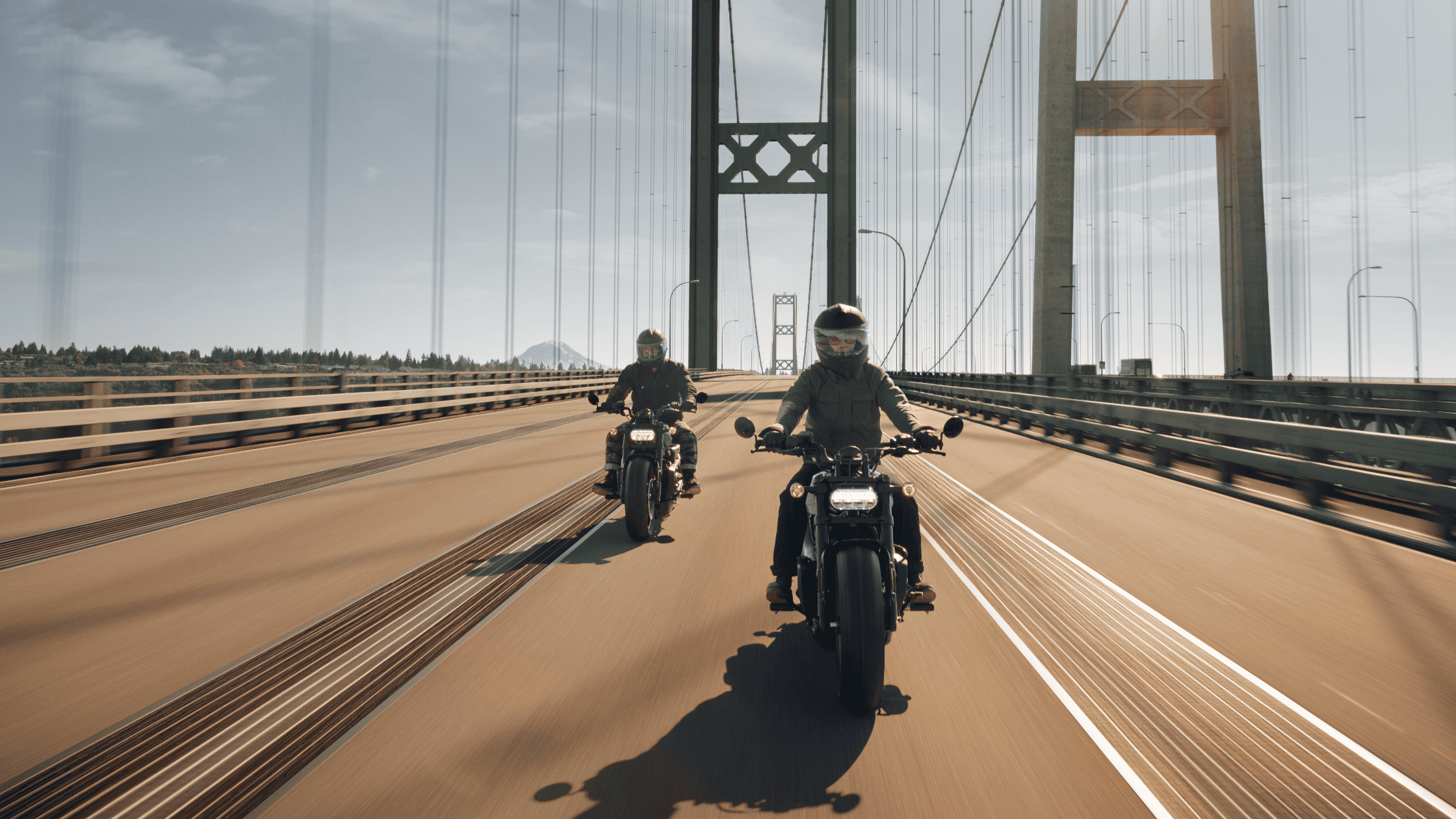 2024 Harley-Davidson® Sportster® S riders crossing a scenic suspension bridge.