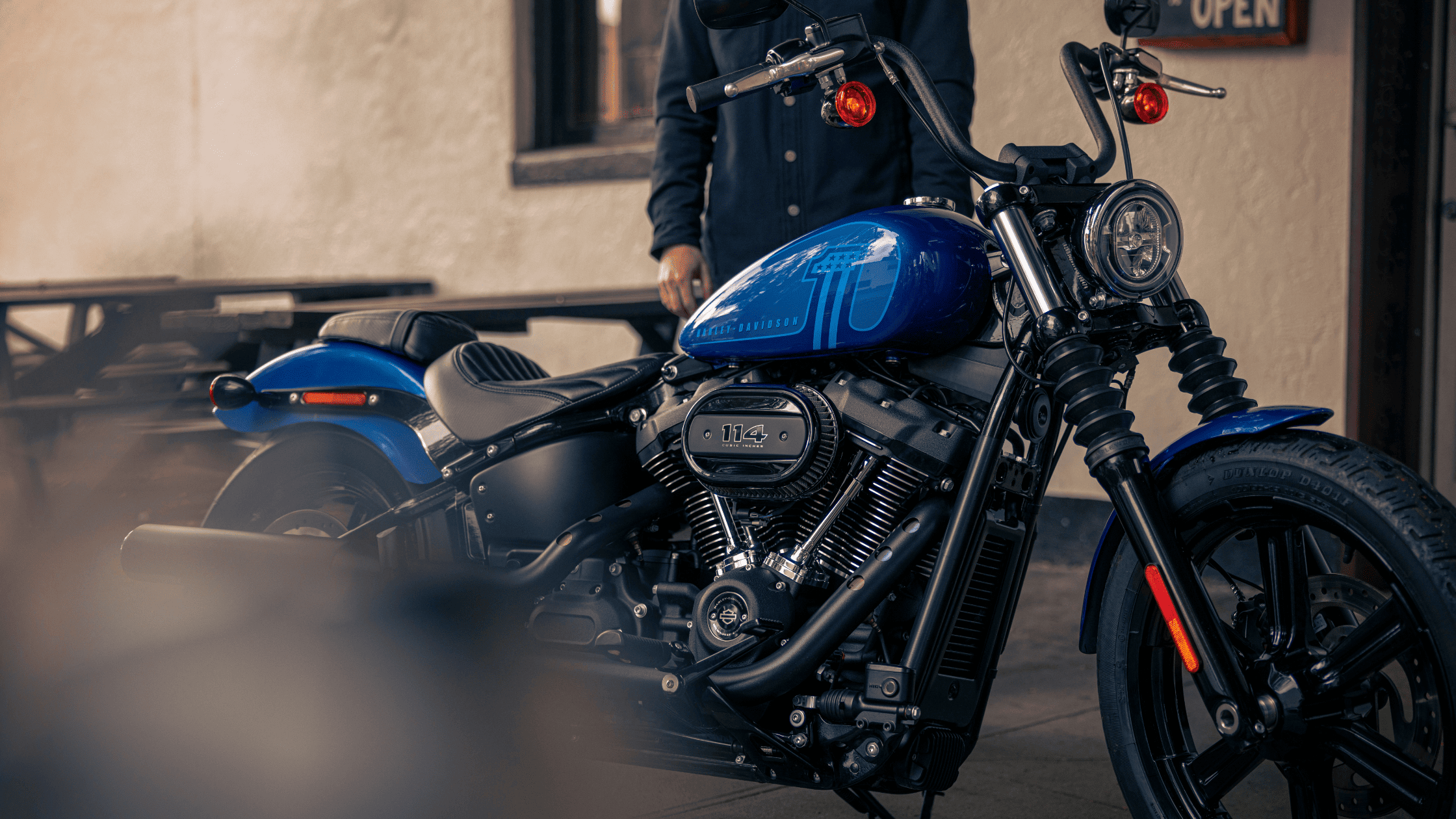 2024 Harley-Davidson® Street Bob® 114 in blue, parked outside with rider nearby.
