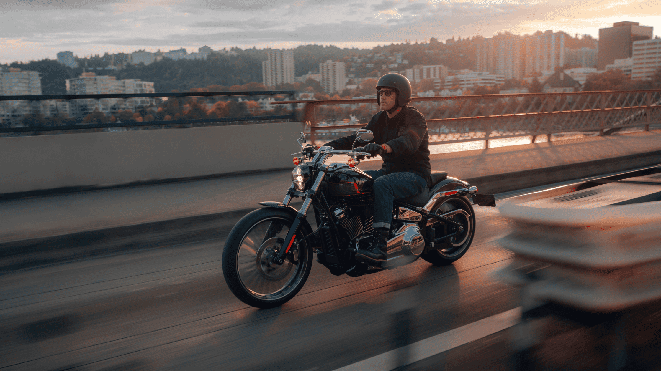 2024 Harley-Davidson® Breakout® 117 cruising city bridge at sunset.