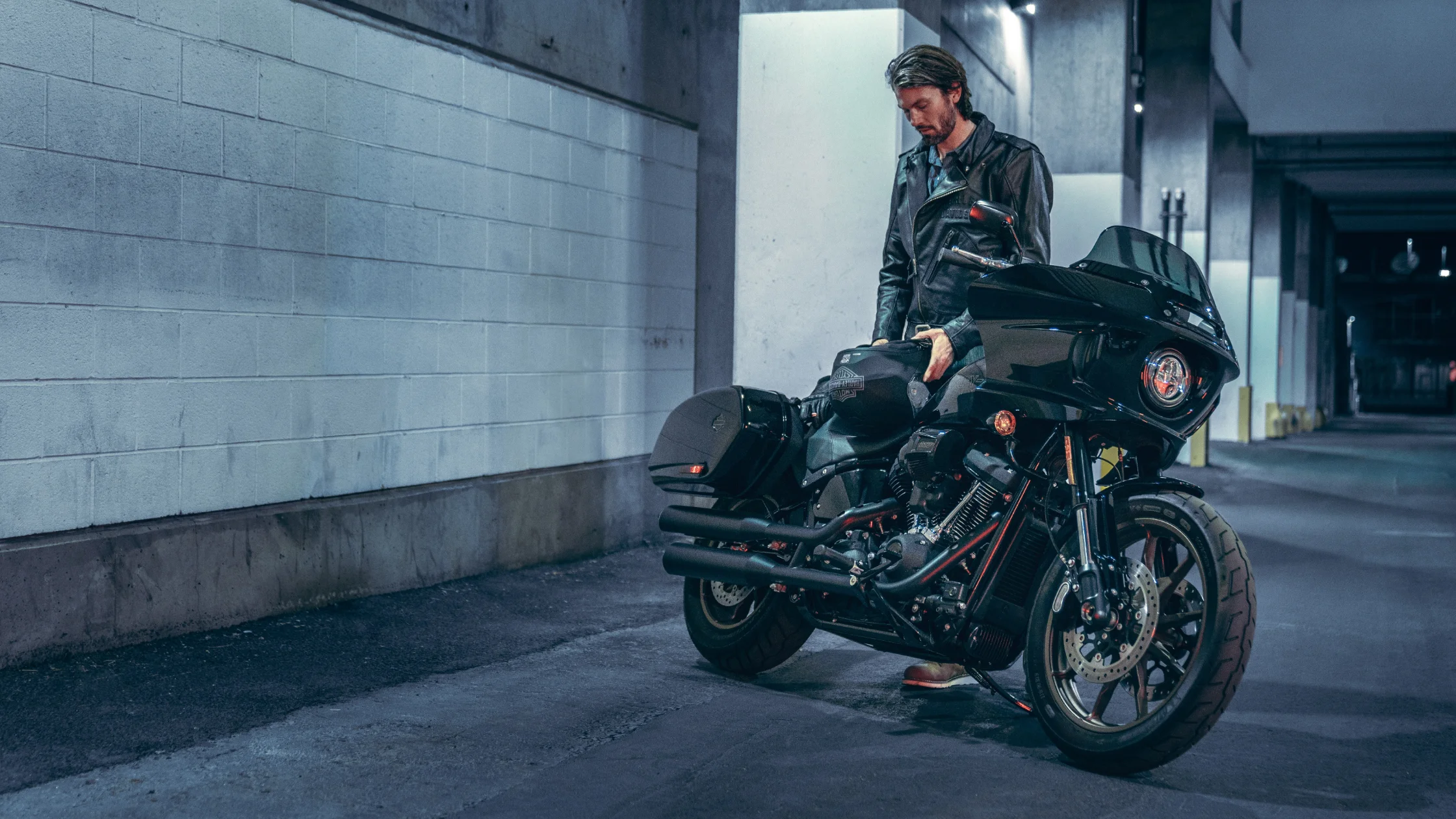 Man in leather jacket with Harley-Davidson Low Rider® ST in urban setting.