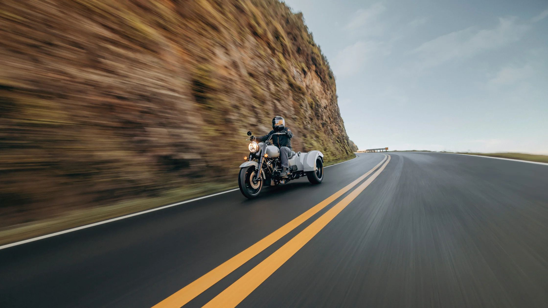 Rider on Harley-Davidson Freewheeler® trike cruising on a winding road.