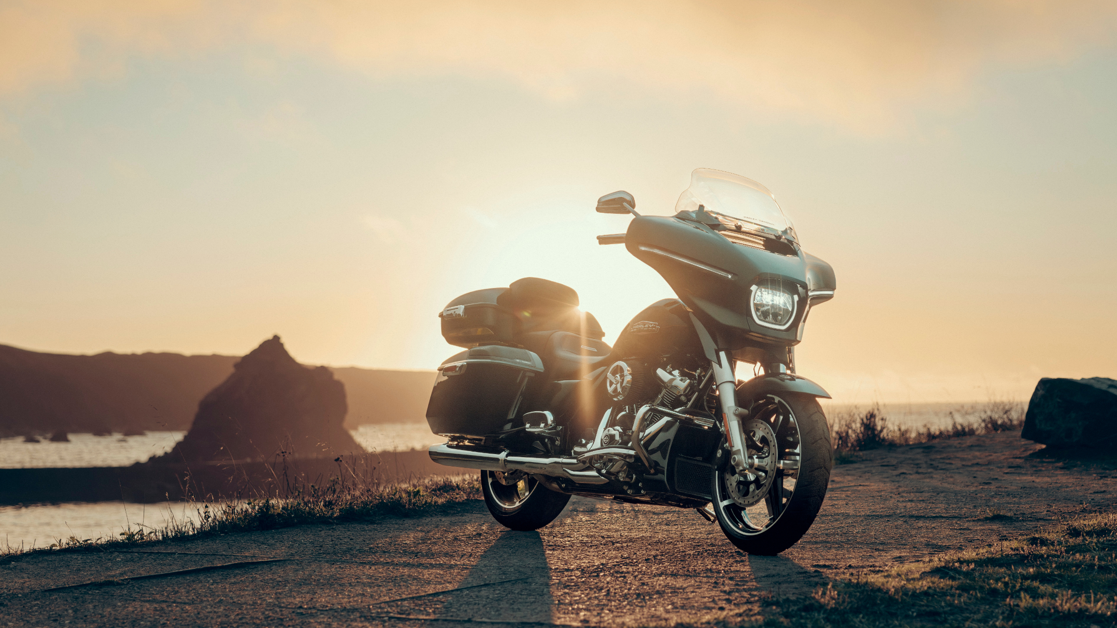 Harley-Davidson® Street Glide® parked by the coast at sunset, showcasing its sleek design and premium features, perfect for scenic rides in Bentonville, AR.