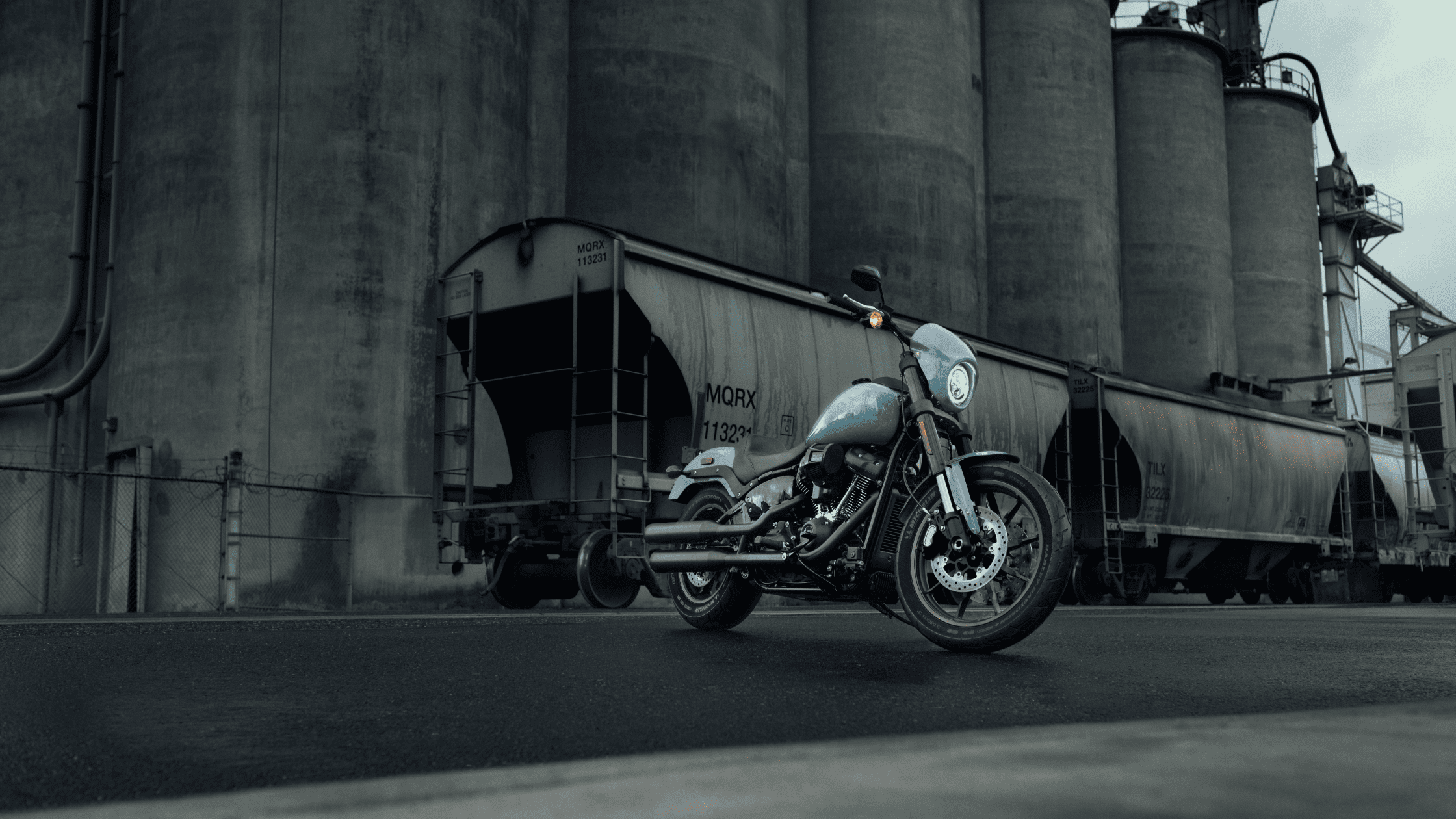 Harley-Davidson Low Rider® S parked near industrial silos, highlighting its rugged design in an urban setting.