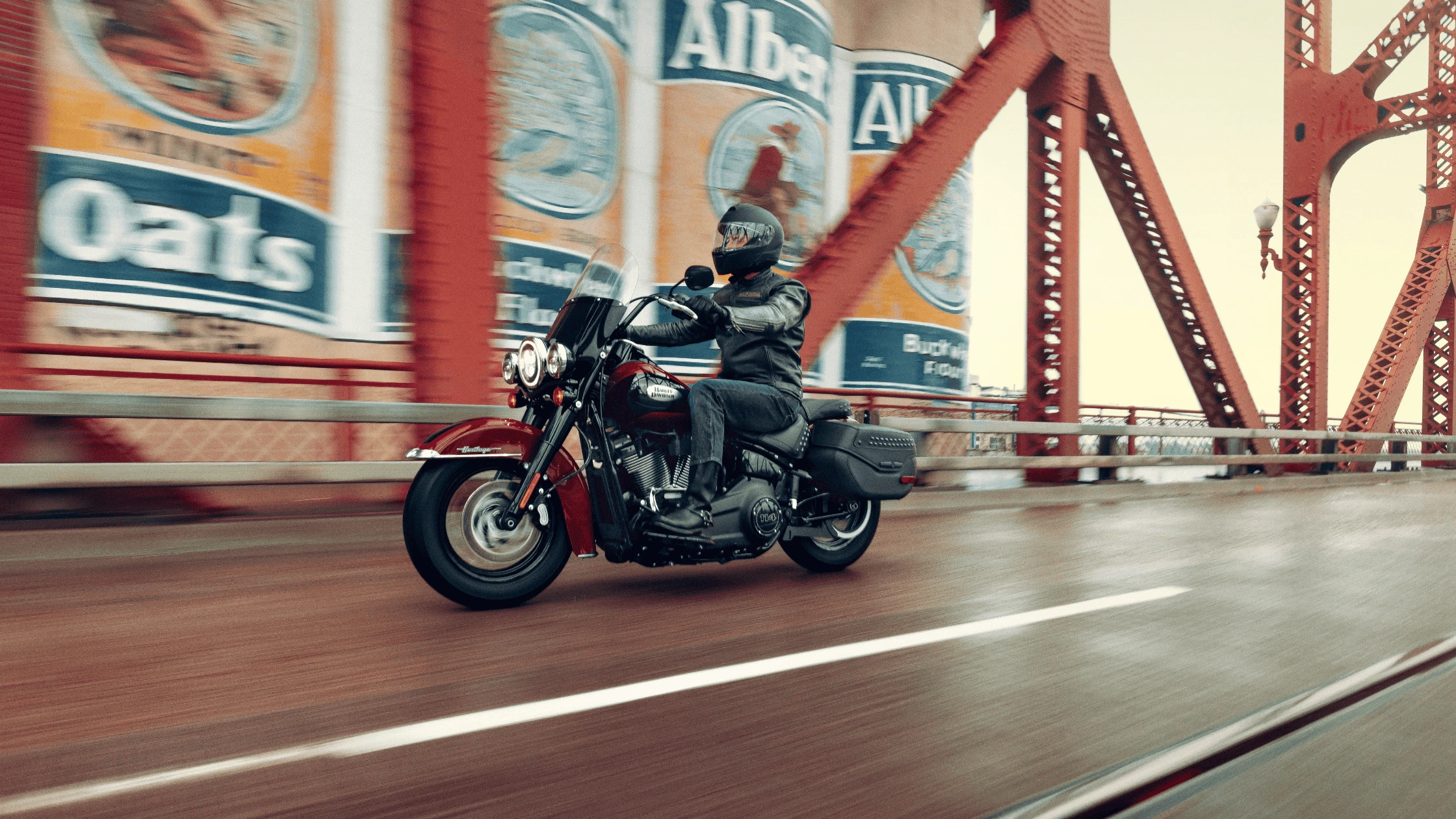 Rider on a 2024 Harley-Davidson® Heritage Classic 114 cruising over a historic bridge, embodying Bentonville’s iconic motorcycle riding culture.