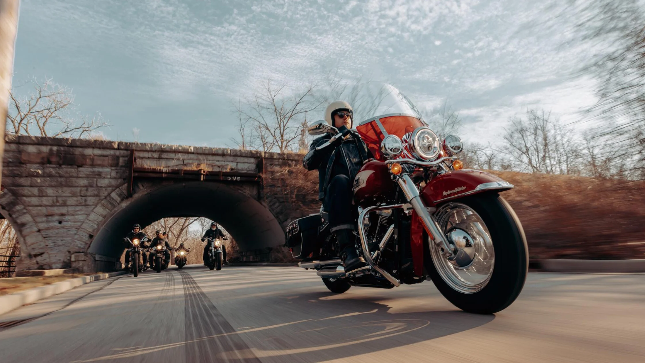 Harley-Davidson® Hydra-Glide Revival leading a group ride under a stone bridge.
