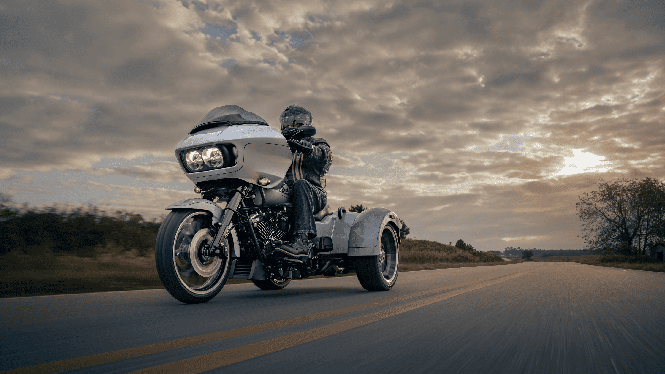 Rider on a Harley-Davidson® Road Glide® 3 cruising at sunset.