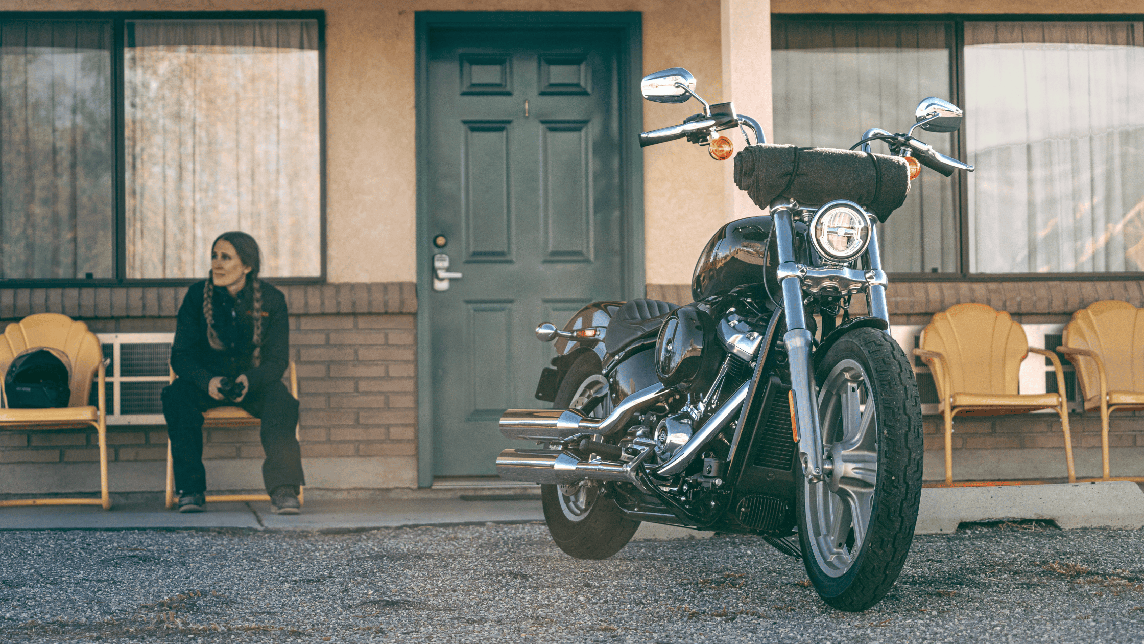 2024 Harley-Davidson® Softail® Standard in classic black parked outside a motel, rider seated nearby