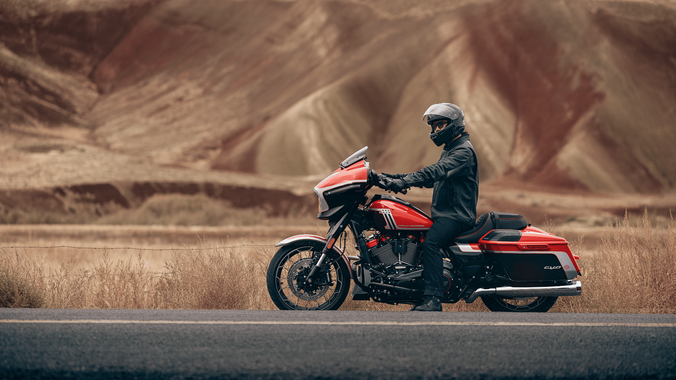 A man in a helmet and jacket rides a red 2024 Harley-Davidson® CVO™ Street Glide® motorcycle