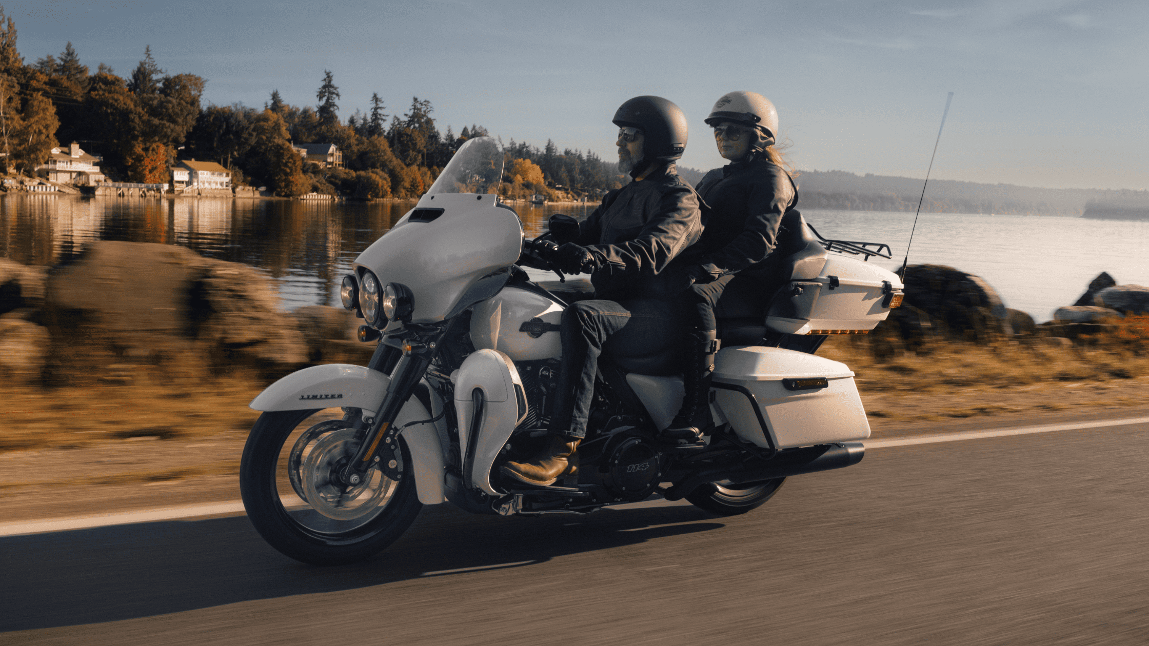 Two individuals riding a white motorcycle along a scenic road, enjoying the open air and freedom of the ride.