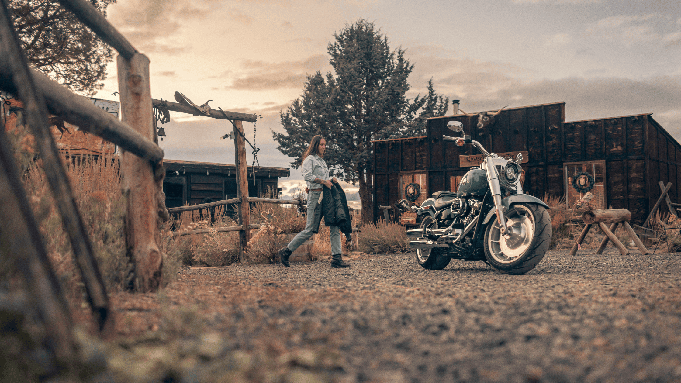 A woman walks beside a motorcycle, enjoying a sunny day and the thrill of the open road.