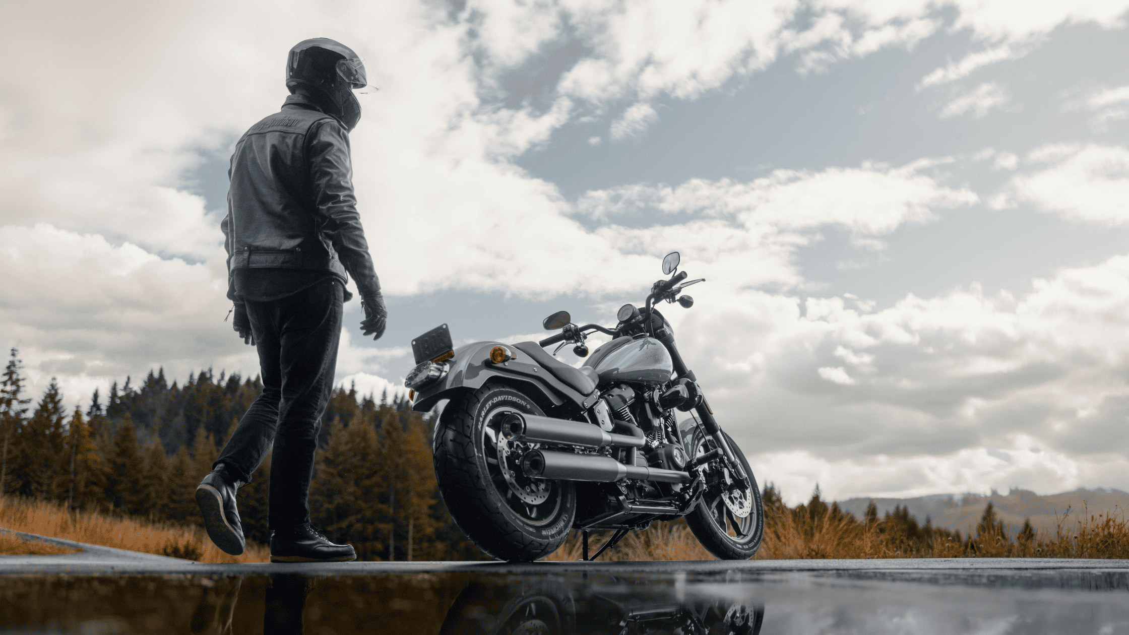 A man poses next to a motorcycle on a road, embodying the spirit of exploration and the open road.