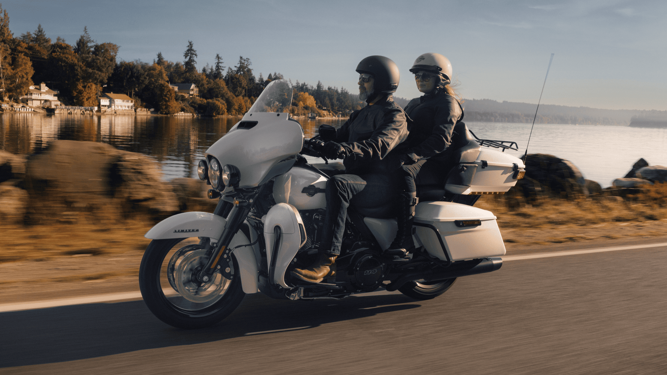 Two individuals riding a white motorcycle along a scenic road, enjoying the open air and freedom of the ride.