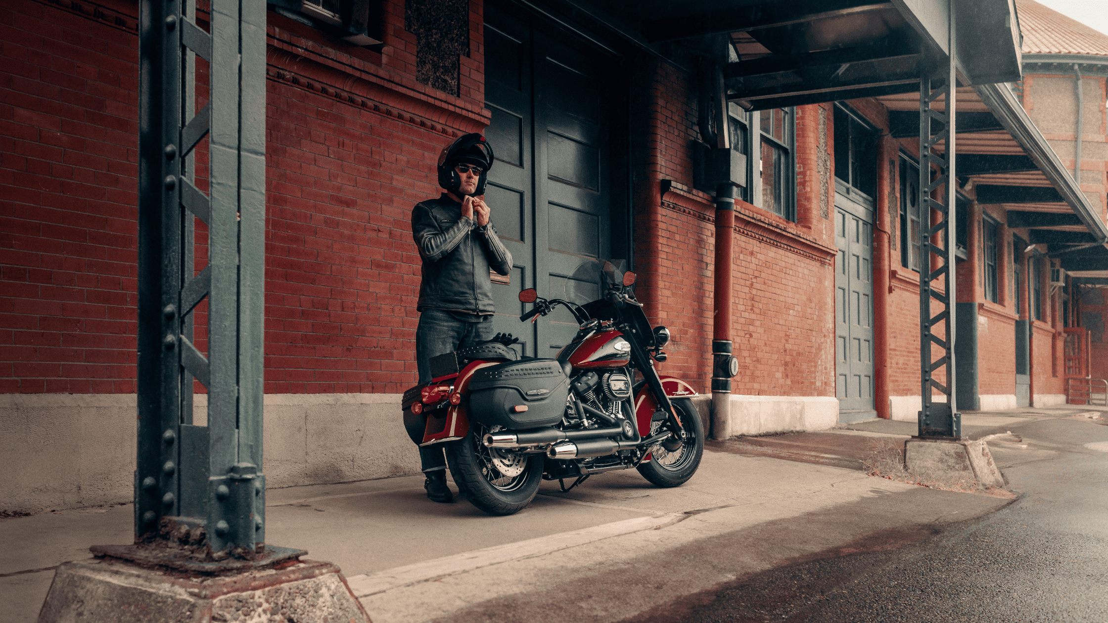 A man stands next to a motorcycle, smiling and enjoying the moment outdoors.