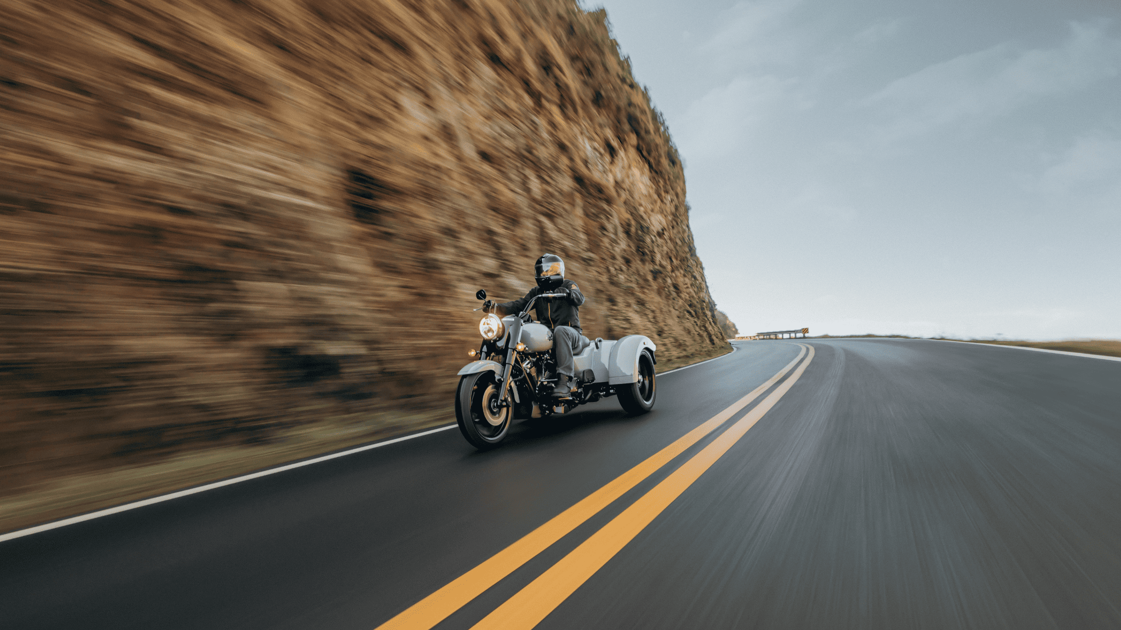 A rider on a Harley Davidson motorcycle travels along a winding road, embracing the thrill of the journey.