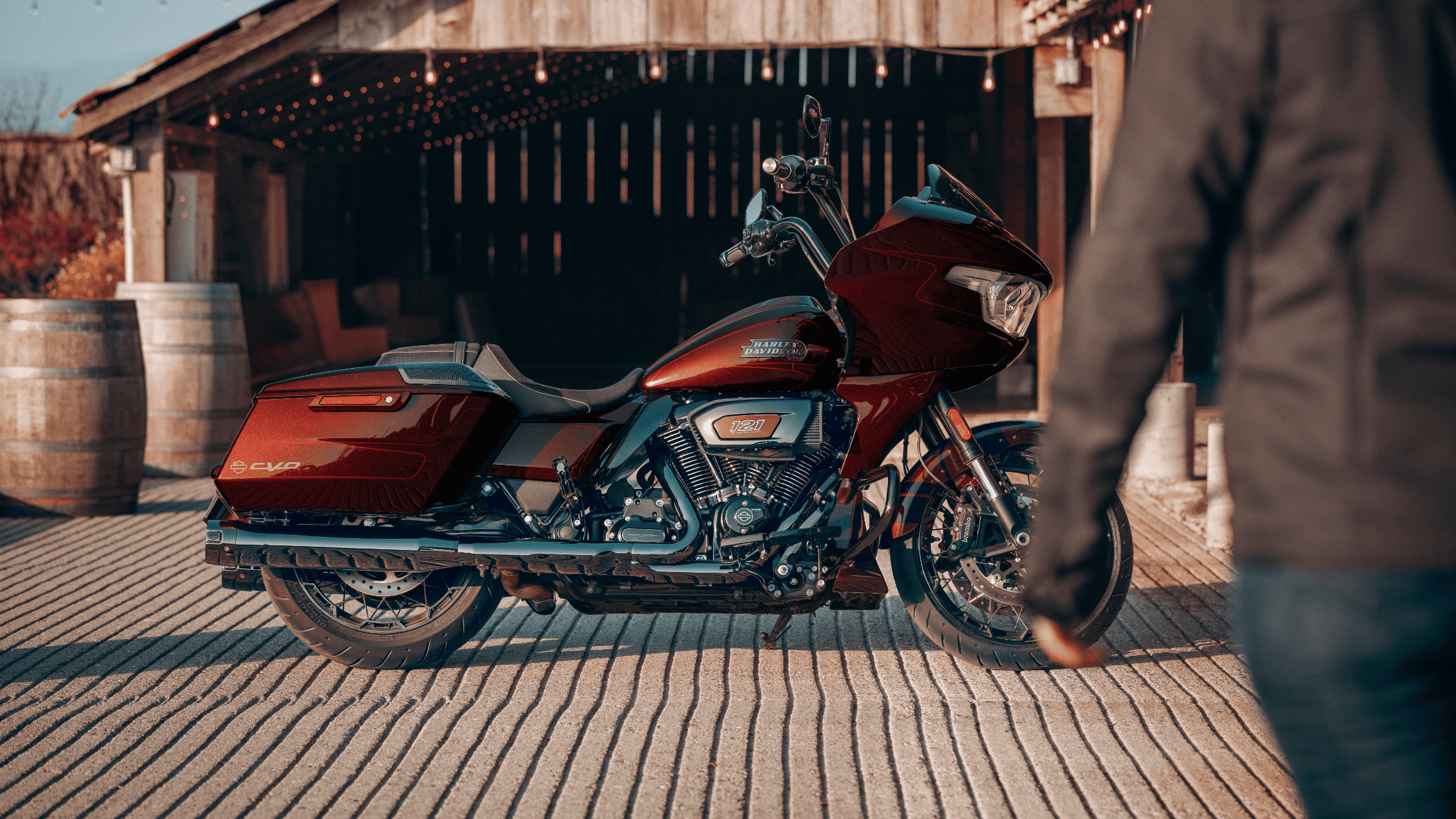 A vibrant red Harley Davidson motorcycle stands parked in front of a classic barn, highlighting its bold color and style.