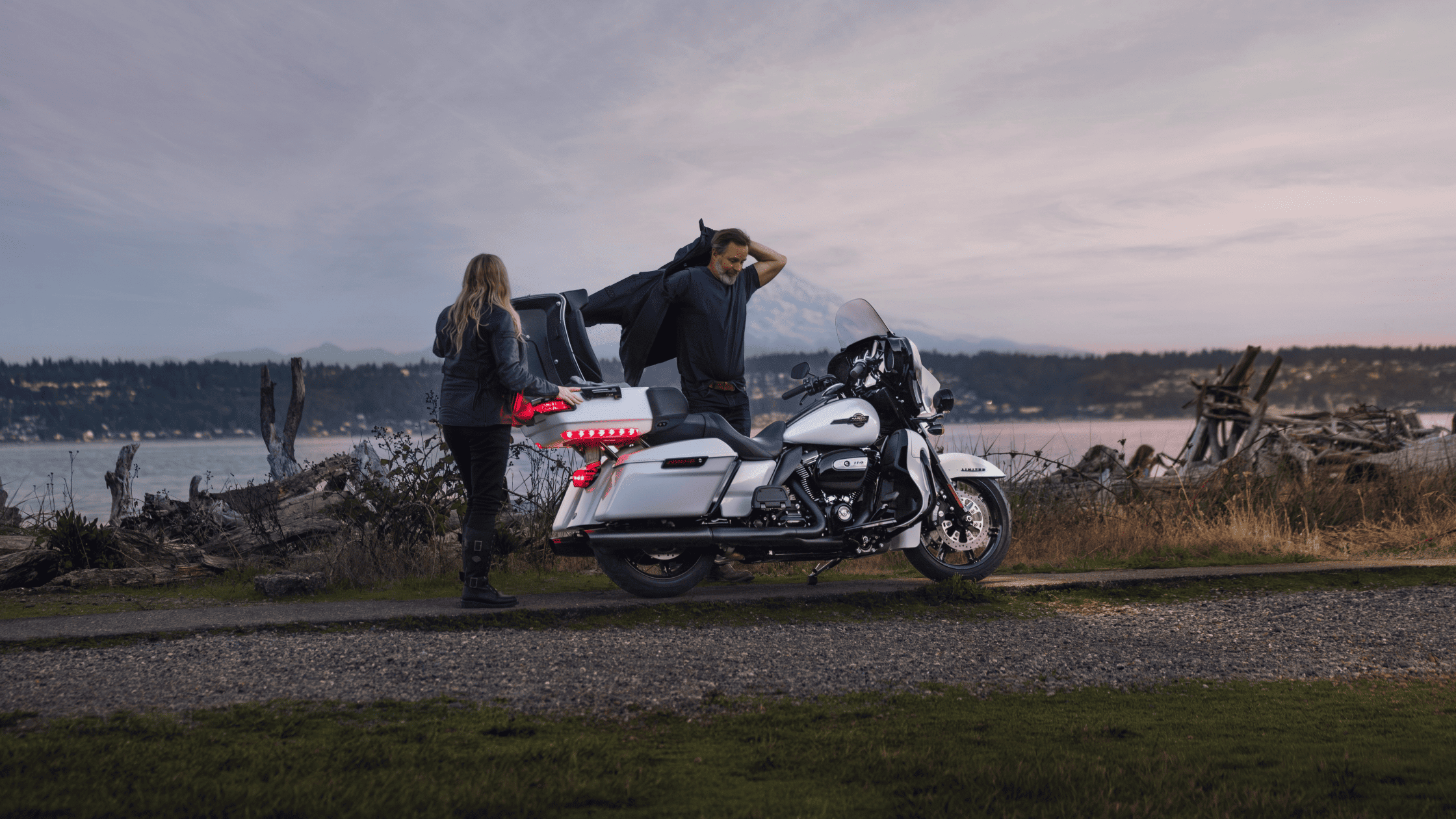 A couple rides a Harley Davidson motorcycle, enjoying the open road together.