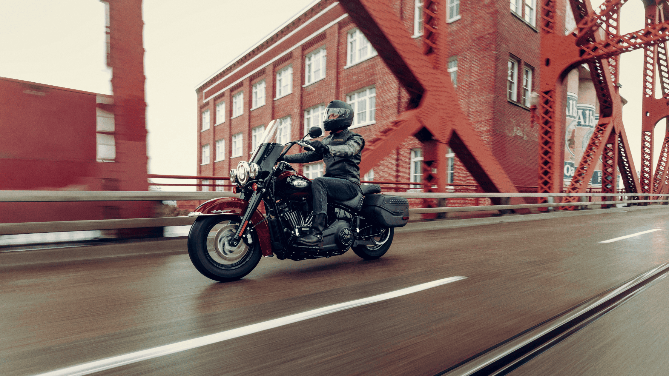 A rider on a Harley Davidson motorcycle crosses a bridge, embracing the thrill of the ride and the fresh air.