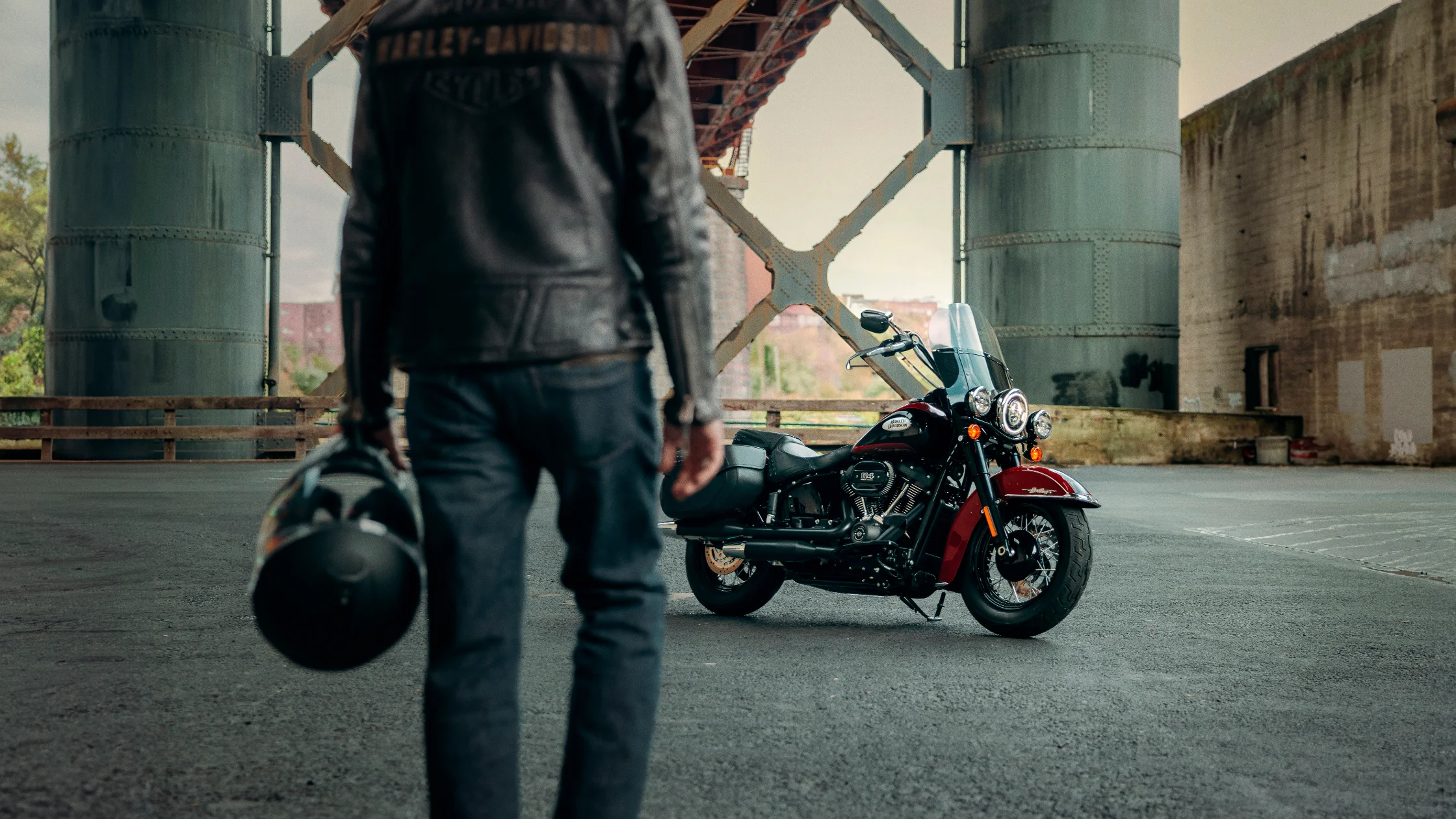 Rider approaches a parked 2024 Harley-Davidson Heritage Classic 114 under a bridge.