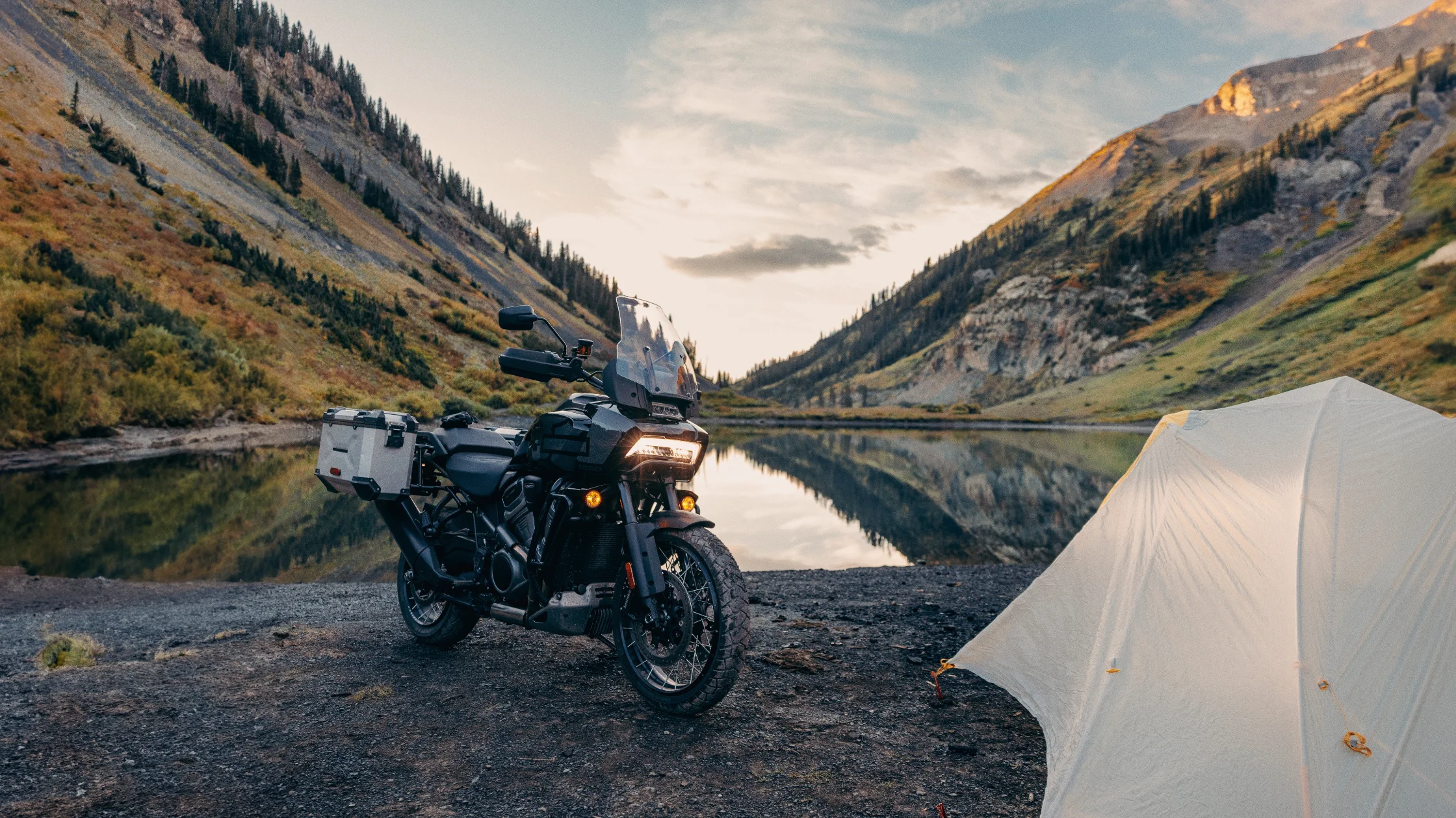 2024 Pan America 1250 Special parked by a scenic mountain lake at sunrise.