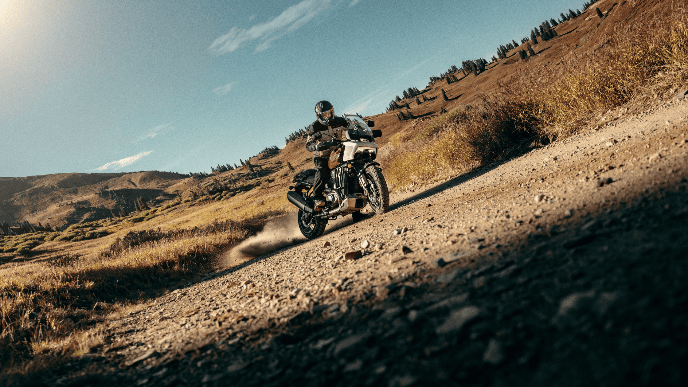 A person confidently rides a 2024 Harley-Davidson® Pan America® 1250 Special along a bumpy dirt road, ready for exploration.