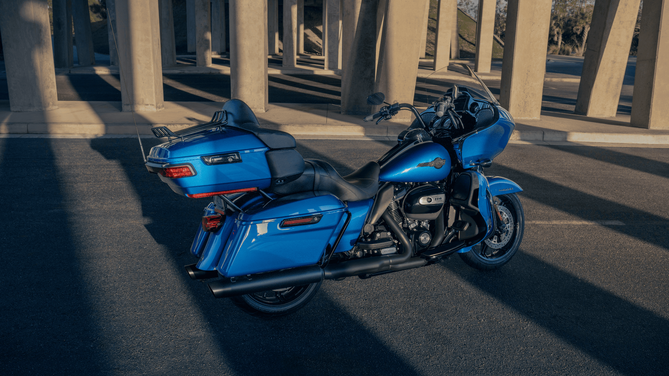 A vibrant blue 2024 Harley-Davidson® Road Glide® Limited parked under a modern concrete structure